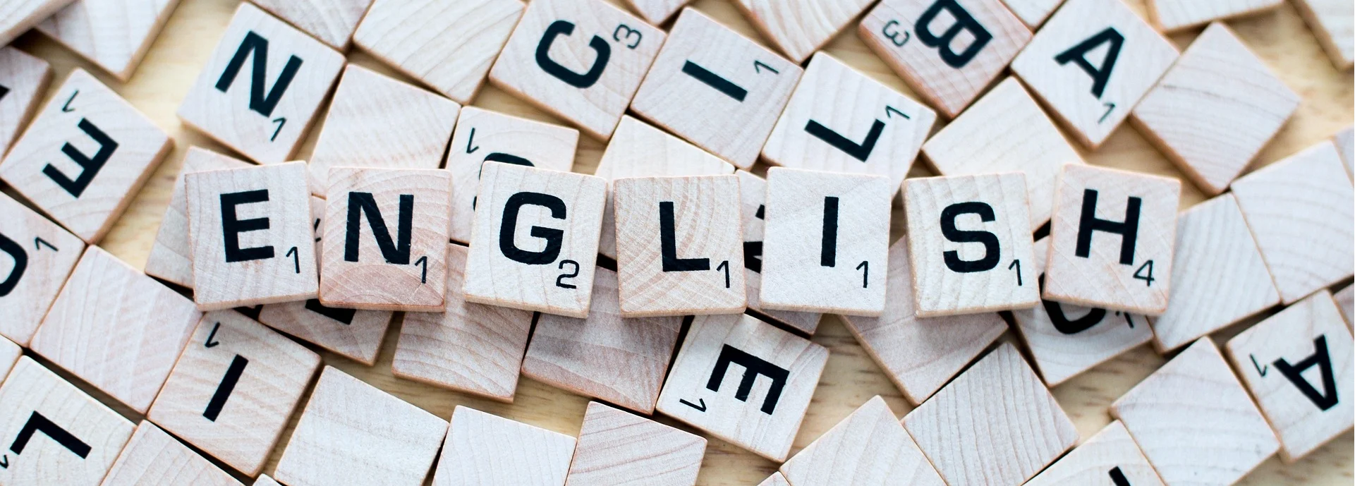 Scrabble letters that spell out the word "English", with a jumble of letters behind - to illustrate an article on editing